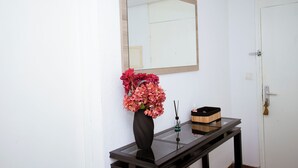 A bathroom with a mirror, a vase with flowers, a soap dispenser, and a wooden box on a black table.