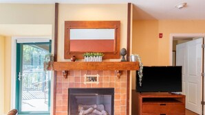 A fireplace with a TV on a wooden stand, a 'HOME' sign above it, and a 'FIRE' sign on the wall. - Lodge style getaway 50 miles from NYC patio 207 (Vernon Township)