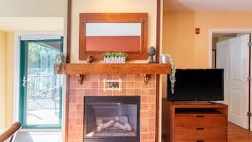 Una chimenea con un televisor sobre un soporte de madera, un letrero que dice 'HOME' encima y un letrero que dice 'FIRE' en la pared.