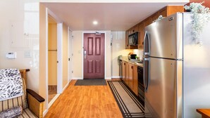 A narrow hallway leading to a door, with a kitchen area featuring a stainless steel refrigerator and wooden cabinets. - Lodge style getaway 50 miles from NYC patio 207 (Vernon Township)