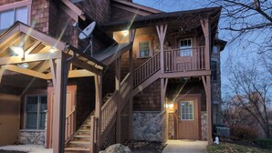 Una casa in legno a due piani con un portico coperto, una scala e fondamenta in pietra.