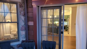 Una stanza con una parete in pietra, una porta scorrevole in vetro che dà su una cucina e due sedie vicino alla porta.
