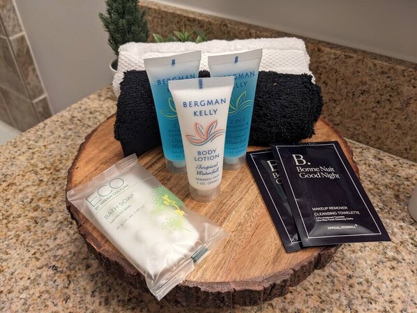 A wooden surface with a bath soap, Bergman Kelly body lotion, and a makeup remover package. - All New Chic Ski in/out King bed (Vernon Township)