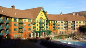 Ett hotell med flera våningar, en iögonfallande gul och grön fasad, en central innergård och en swimmingpool.