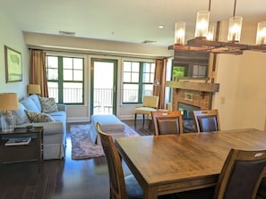 A living room with a wooden dining table, a sofa, a coffee table, and a fireplace.