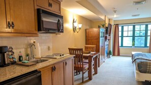 A kitchen with wooden cabinets, a microwave, and a dining area with chairs and a table.