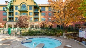Um hotel com piscina, cerca verde e folhagem de outono.