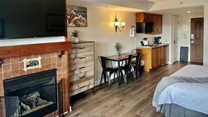 Ein Hotelzimmer mit Kamin, Essbereich, Küche und einem Bett.