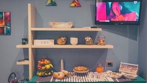 A breakfast buffet with various food items, a television displaying a program, and decorative wall art. - Cozy B&B,right in the center & within walking distance of beautiful sea of Gaeta (Gaeta)