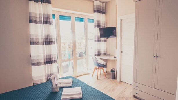 A bedroom with a bed, a chair, a TV, and a wardrobe. - Cozy B&B,right in the center & within walking distance of beautiful sea of Gaeta (Gaeta)