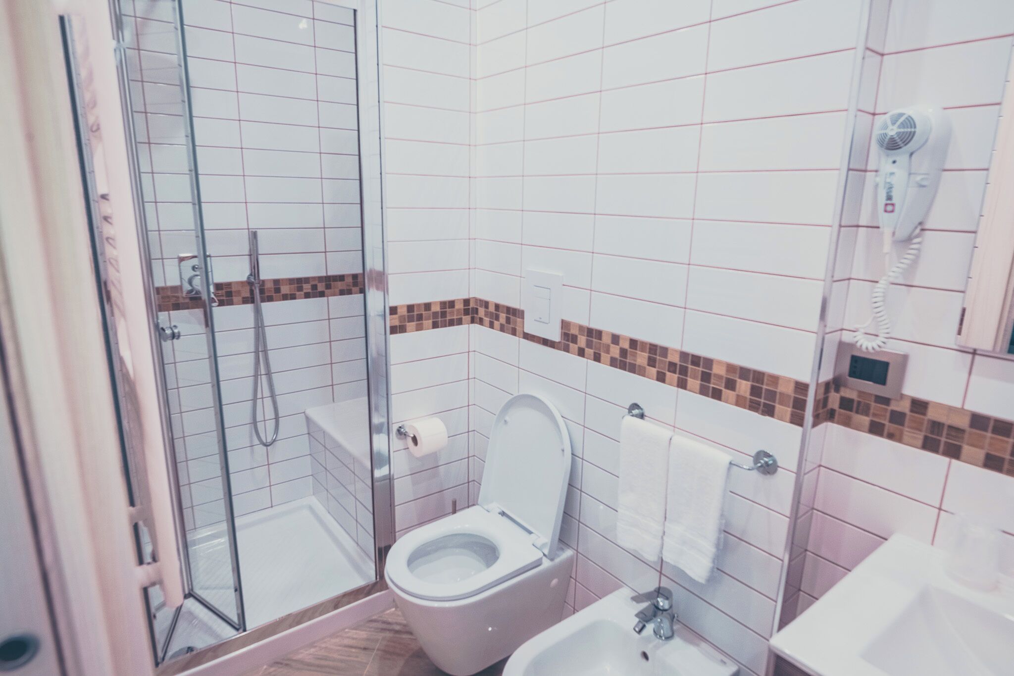 Kylpyhuone, jossa on lasiseinällinen suihkukaappi, wc, bidee ja pesuallas.