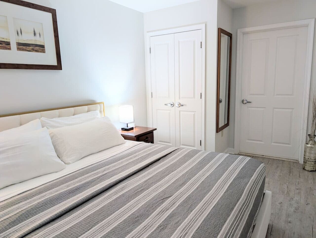 Ein Schlafzimmer mit einem Bett, einem Nachttisch und zwei weißen Türen.