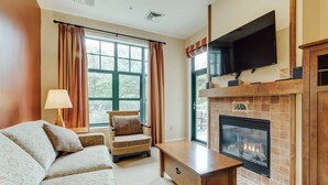 A living room with a fireplace, a sofa, a chair, and a television. - RARE 1st flr Private Ski in/out access 1 Bed! (Vernon Township)