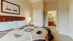 A hotel room with a large bed, a nightstand with a lamp, a door leading to a bathroom, and a framed picture on the wall. - RARE 1st flr Private Ski in/out access 1 Bed! (Vernon Township)