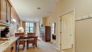 A kitchen with wooden cabinets, a dining table, chairs, and a window. - RARE 1st flr Private Ski in/out access 1 Bed! (Vernon Township)