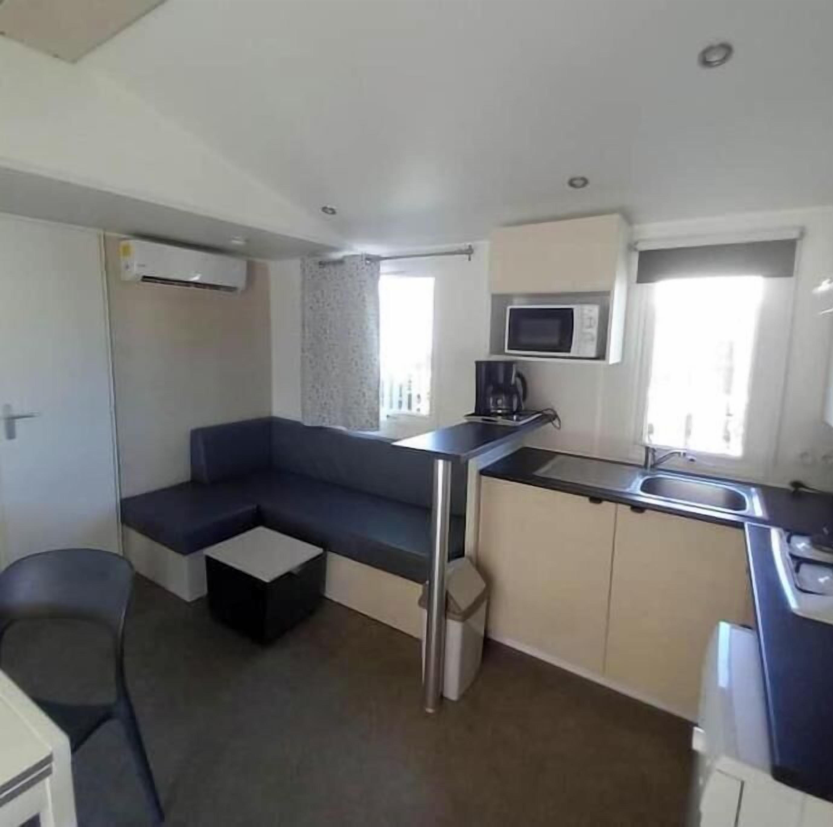 A compact kitchen with a microwave, coffee maker, and a small sink.