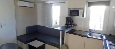 A compact kitchen with a microwave, coffee maker, and a small sink.