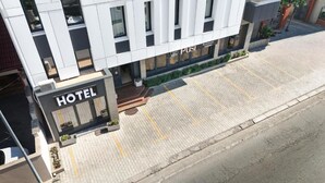 A modern hotel with a prominent 'HOTEL' sign, a paved entrance, and a visible restaurant sign. - Pusi Hotel (Tirana)