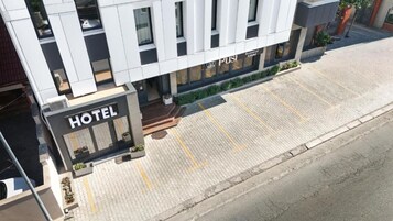 Un hotel moderno con un llamativo letrero 'HOTEL', una entrada pavimentada y un letrero de restaurante visible.