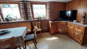 A cozy kitchen with wooden cabinets, a dining table, and a TV. - Haus Gloriosa: Where Black Forest tradition meets pure relaxation. (Bonndorf im Schwarzwald)