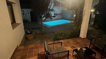 Una terrazza con piscina, mobili da esterno e una lampada a sospensione.