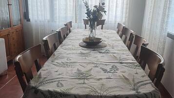 Un comedor con una mesa larga, sillas, un armario y cortinas.