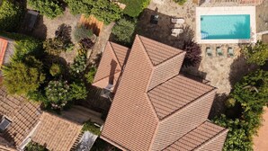 Luchtbeeld van een woonhuis met een zwembad, verschillende dakvlakken en omliggend groen.