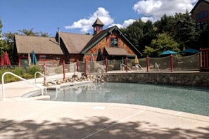 A swimming pool with a stone border, a wooden building with a red roof, and a fenced area with umbrellas. - Top floor Family 3 Bed w/4 Bunks (Vernon Township)