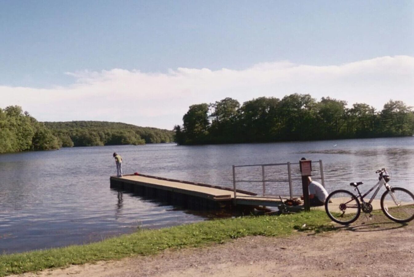 A dock extending into a lake with a bicycle parked nearby.