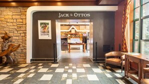 Un hall d'hôtel avec un sol à carreaux, un mur en pierre et une enseigne « Jack & Ottos ».