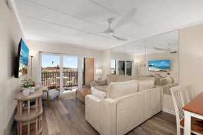 Ein modernes Wohnzimmer mit einer Couch, einem Esstisch und einem Fernseher. Es gibt einen Balkon mit Blick.
