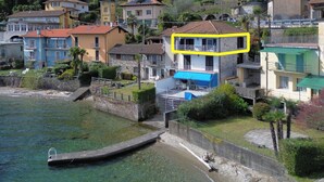 A coastal residential area with houses, a clear view of the sea, and a dock. - Apartment Carmine sul Lago (Carmine)