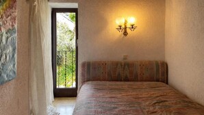 A bedroom with a bed, a window with a view, and a wall-mounted light fixture. - Apartment Carmine sul Lago (Carmine)