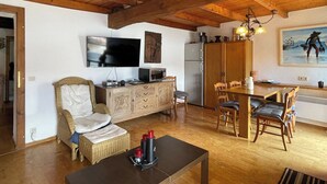 A cozy living area with a television, a dining table, and a wicker chair. - Apartment Carmine sul Lago (Carmine)