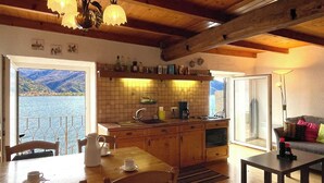 A cozy kitchen with wooden cabinets, a sink, and a coffee maker. There is a dining table with chairs and a sofa in the living area. - Apartment Carmine sul Lago (Carmine)