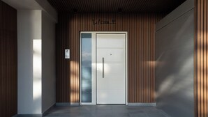 Une entrée moderne avec une double porte, un lambris vertical en bois et un sol carrelé.