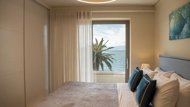 Une chambre d’hôtel avec un lit, des rideaux, un tableau et une vue sur la mer.
