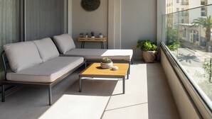 Un balcon avec un canapé, une table en bois et des plantes en pot.
