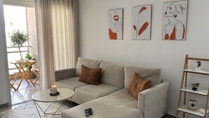 Un salon moderne avec un canapé d’angle, une petite table ronde, une télécommande et un luminaire décoratif suspendu.