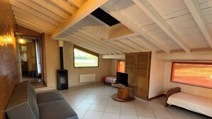 Un vaste espace de vie doté d’un haut plafond, d’une cheminée, d’un canapé, d’une télévision et d’une fenêtre.