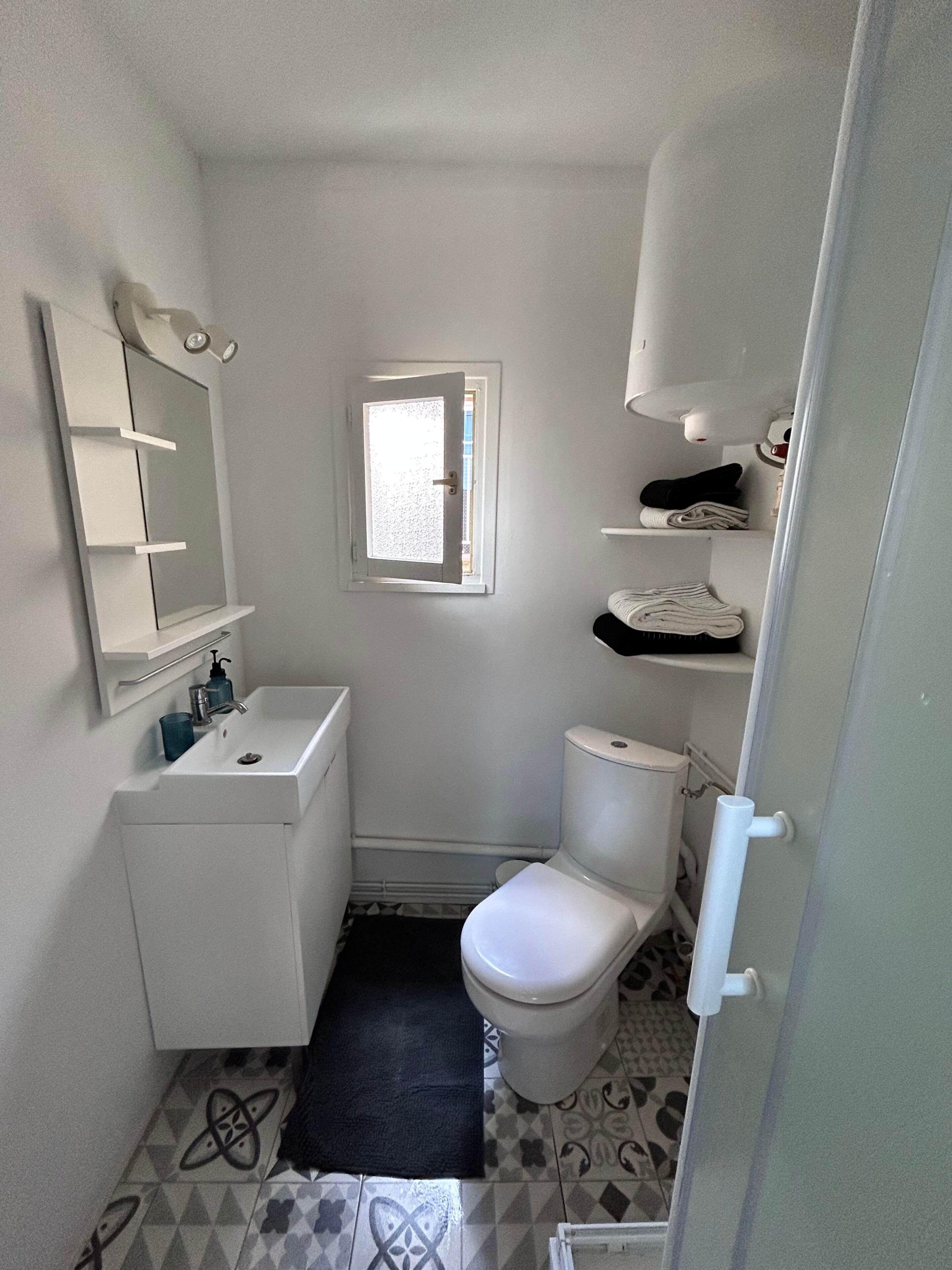 Een kleine, witte badkamer met toilet, wastafel en spiegel.