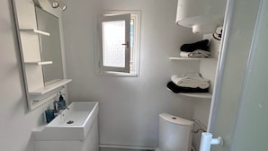 Een kleine, witte badkamer met toilet, wastafel en spiegel.