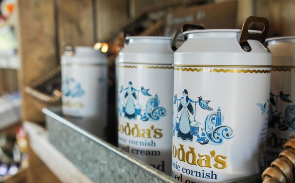 Een rij witte containers met blauwe designs en tekst, aangeduid als 'Boda's Cornish Cream'.