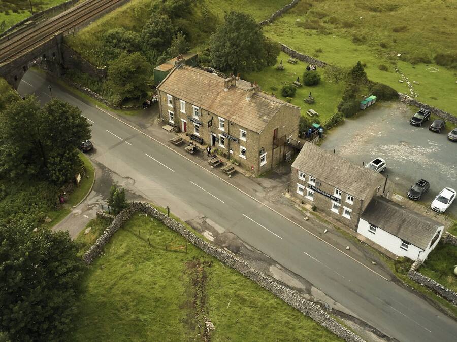 An aerial view of a building with a sign 'Station Inn Bank Bar' and a parking area with vehicles.