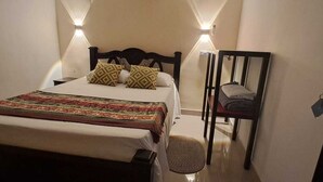 A small, narrow hotel room with a single bed, a chair, and a mirror. - Hostal Caimán del Rio (Barranquilla)