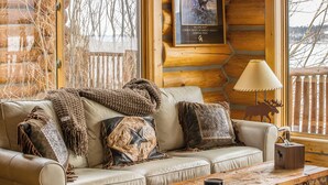 A log cabin interior with a leather sofa, decorative pillows, a wooden coffee table, and a framed picture on the wall. - Hebgen Lakeshore Retreat (West Yellowstone)