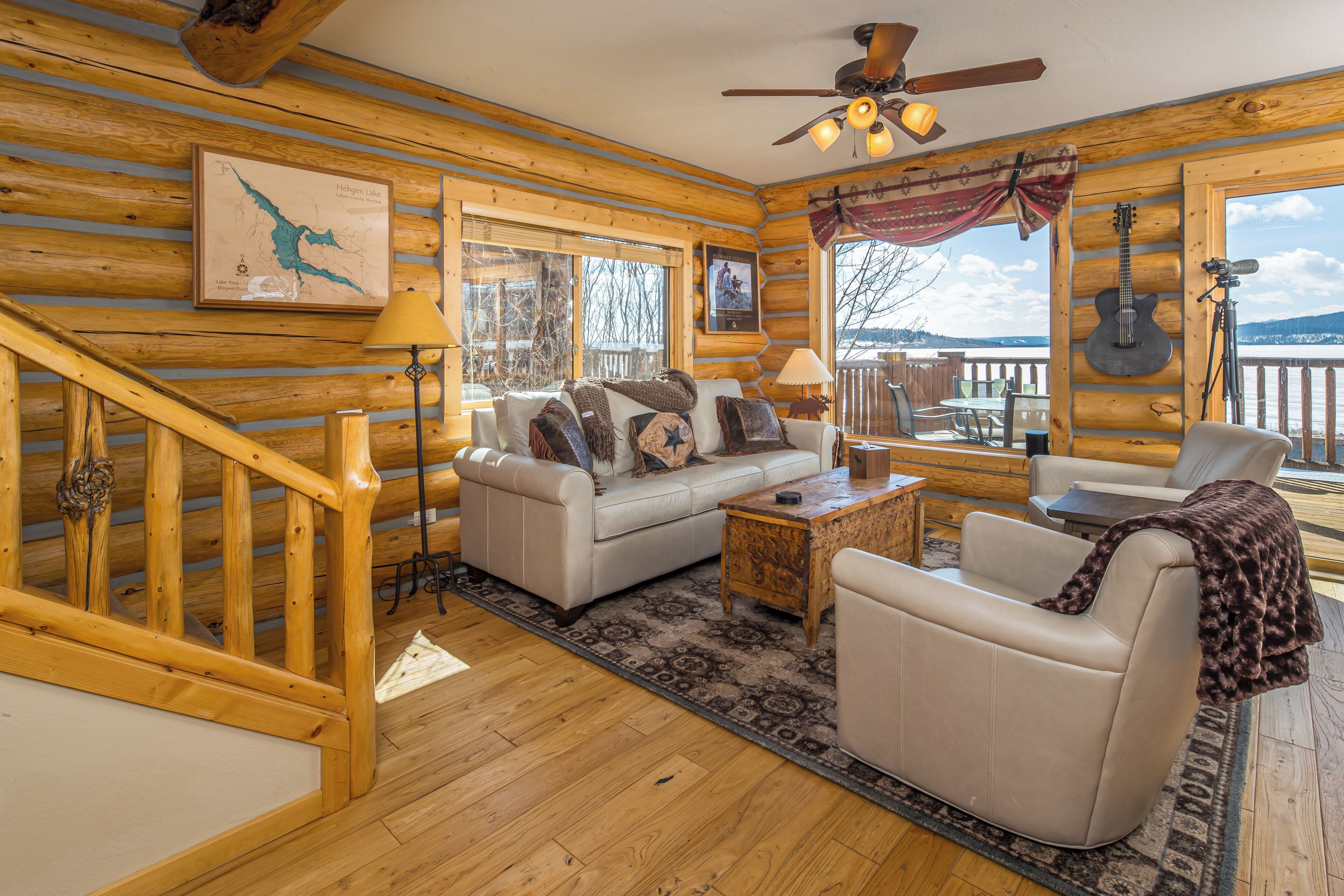 A log cabin interior with a sofa, armchair, and a dining table.