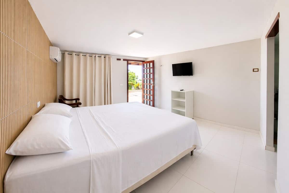 A bedroom with a bed, a TV, a wardrobe, and a window with curtains.