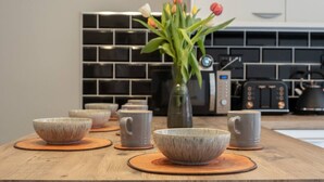 A kitchen with a wooden countertop, ceramic bowls, a vase with flowers, and modern appliances. - Stylish house with Backyard + 4 min walk to Beach (Great Yarmouth)