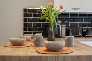 Eine Küche mit einer Holzausziehtafel, Keramikschüsseln, einer Blumenvase und modernen Geräten.